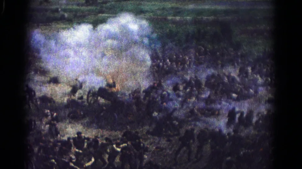 1966 Hagerstown 8mm frame showing a distant crowd or uniformed group amid smoke and small fire on open terrain.