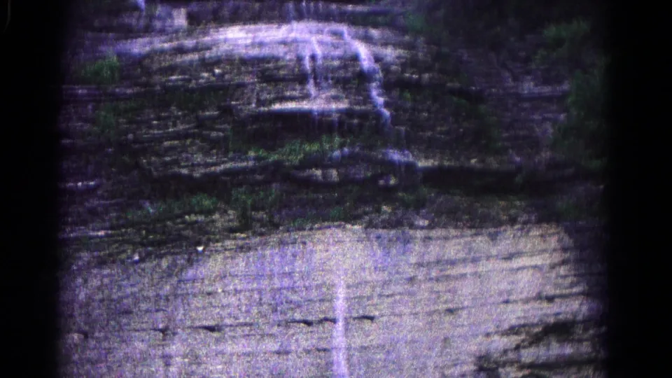 The final 1966 8mm frame lingers on layered Maryland rock, a narrow water stream, surrounding trees, and a pale wet foreground surface.