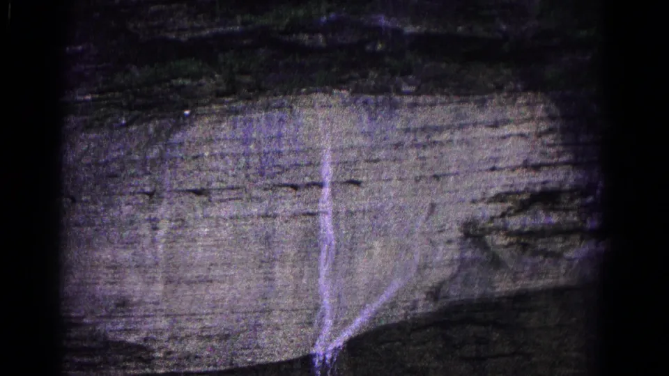 Grainy 1966 8mm view from Hagerstown showing trickling water over a steep, horizontally banded rock wall.