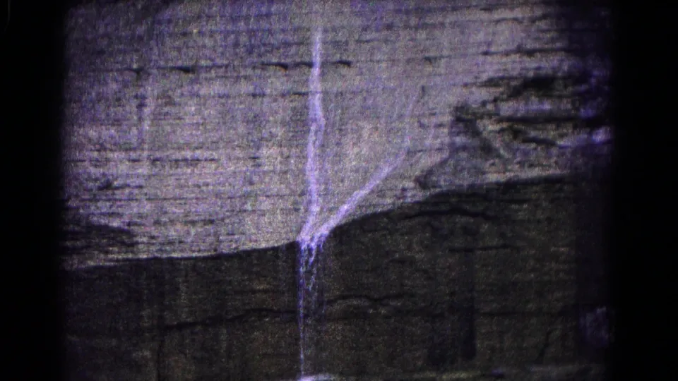 1966 Hagerstown 8mm frame showing water spilling over a rugged layered cliff face with dark gate-edge shadow.