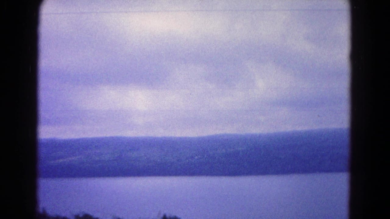Distant ridgeline beyond a wide body of water under a cloudy sky.