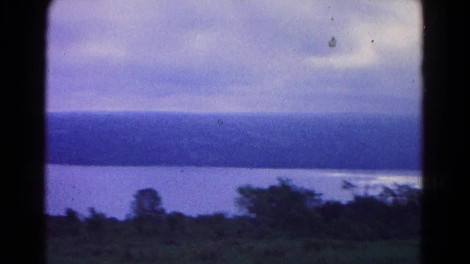 1966 8mm waterfront landscape near Hagerstown with broad blue-gray sky, water, distant shore, trees, and grass in the foreground.