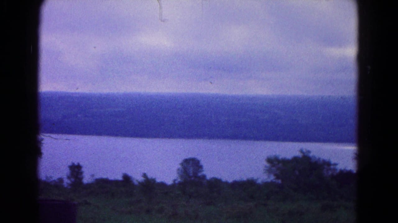 1966 8mm view near Hagerstown, Maryland, showing still water, a wooded ridge, heavy clouds, and dark foreground brush.
