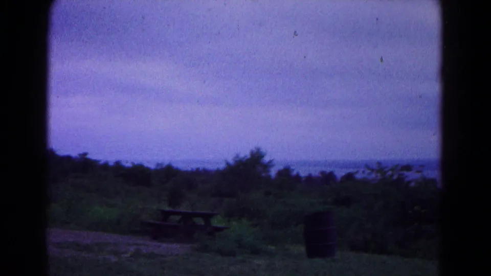 1966 Hagerstown-area home-movie frame showing a rural overlook with picnic table, barrel, trees, and distant horizon.