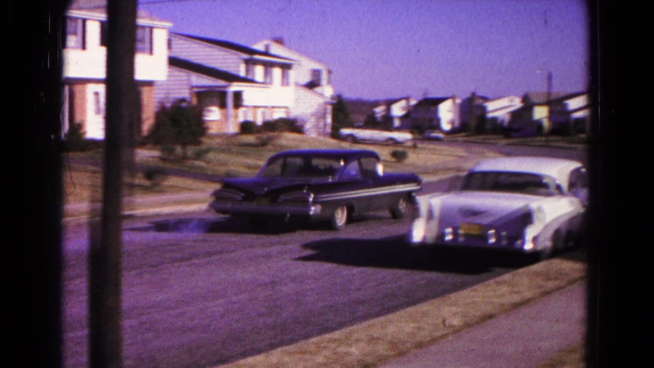 Classic cars move through a 1966 Hagerstown residential block with lawns, sidewalks, and detached houses.