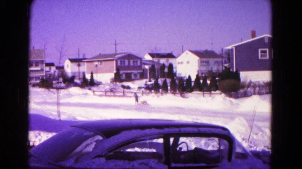 1966 Hagerstown 8mm frame showing a snow-covered foreground car and a person with dog in a suburban winter street.