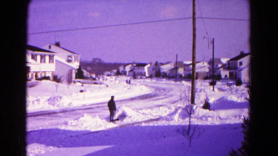 Hagerstown winter street scene with a man at the curb, snow piled high, and rows of detached houses in the background.