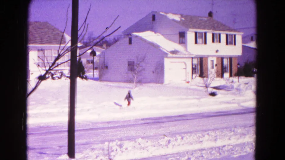 A wide 8mm view shows a small bundled figure crossing or working near a snowy street, with suburban houses in Hagerstown behind them.