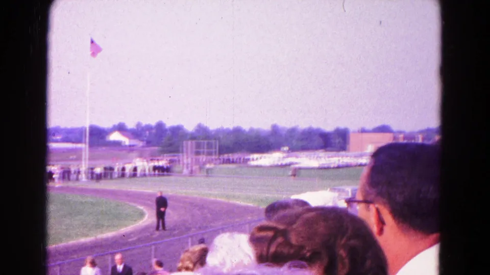 1966 Hagerstown school ceremony seen from the stands, with spectators in the foreground, a flagpole, track, and field beyond.