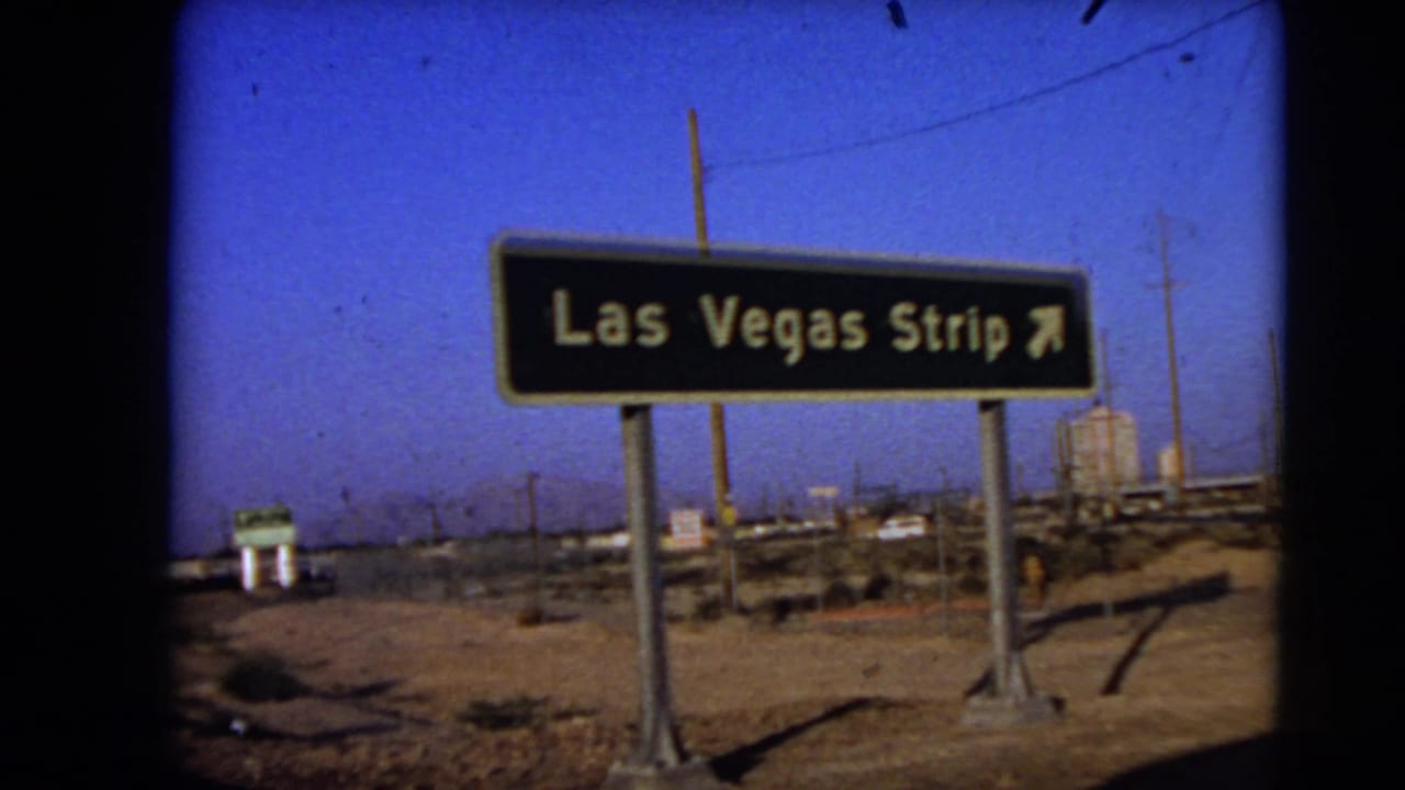Closer view of a Las Vegas Strip directional sign with desert roadside in the background.