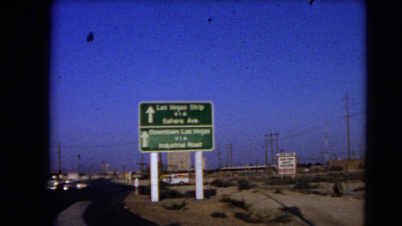 1966 Las Vegas roadway sign showing routes toward the Strip via Sahara Avenue and Downtown Las Vegas via Industrial Road.