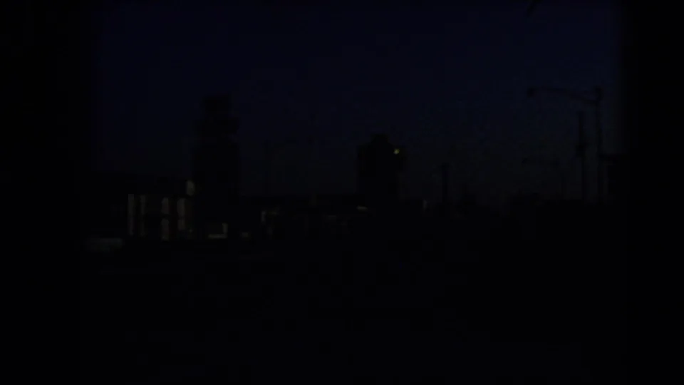 Dark 1966 Las Vegas street approach with city structures mostly in silhouette against a blue twilight sky.