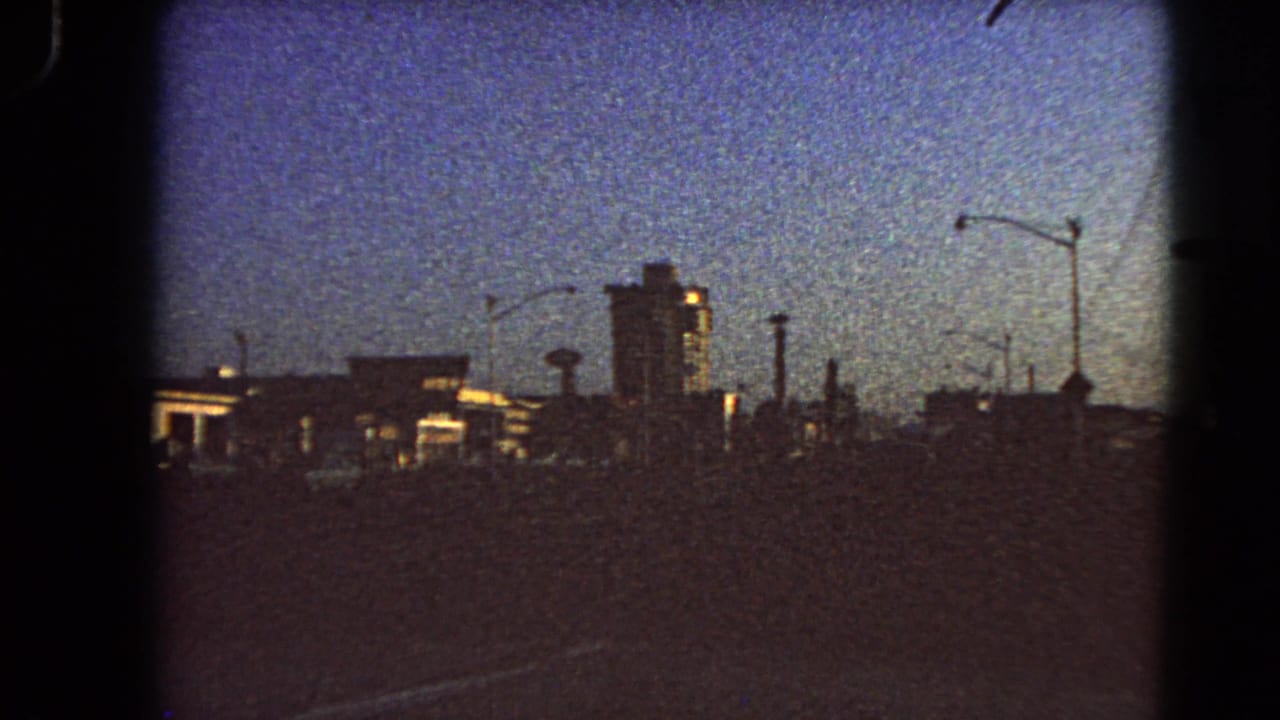 Silhouetted city skyline with streetlights and a tall building at sunrise.