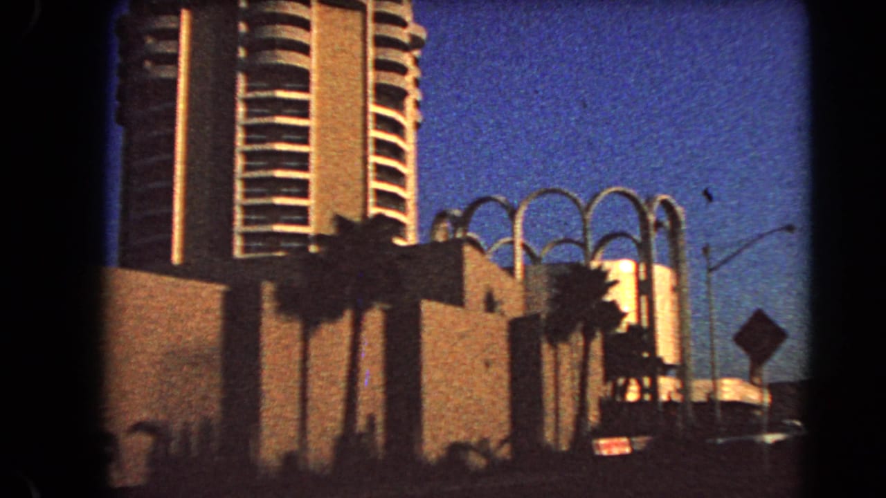 High-rise tower, palms, arched facade, and street edge in evening light.