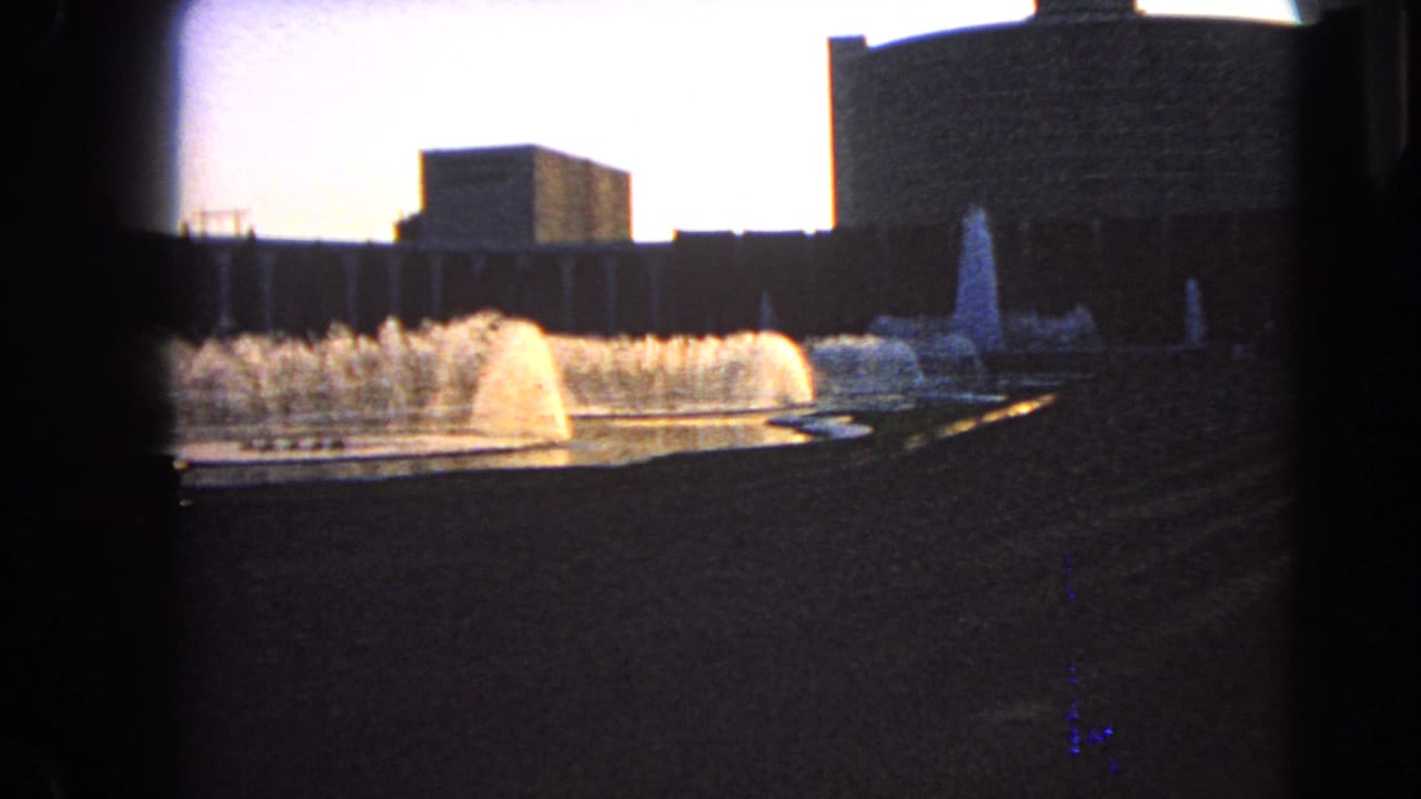 1966 Las Vegas fountain scene with multiple water jets, a curved basin edge, and dark building silhouettes.