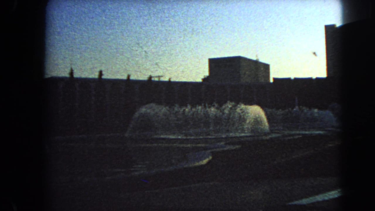 Las Vegas home-movie frame from 1966 showing low fountain spray, a blocky structure, and dark silhouetted architecture.