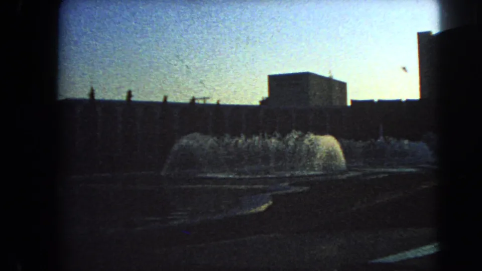Las Vegas home-movie frame from 1966 showing low fountain spray, a blocky structure, and dark silhouetted architecture.