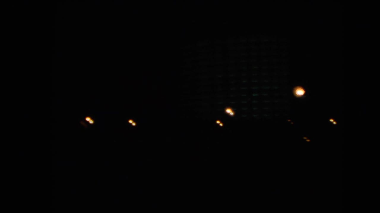 Dark 1966 Las Vegas night frame with scattered city lights and a faintly visible building form against the black background.