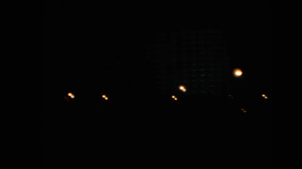 Dark 1966 Las Vegas night frame with scattered city lights and a faintly visible building form against the black background.