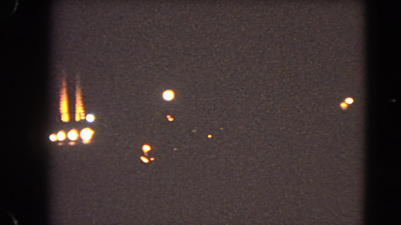 1966 Las Vegas Strip night view with soft distant neon, dark sky, and visible film gate borders from 8mm home-movie footage.
