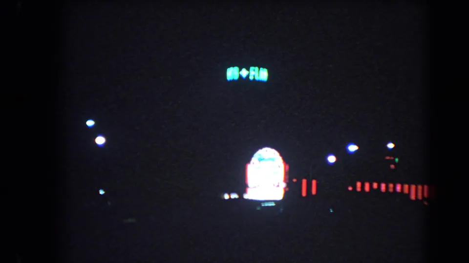 Distant Las Vegas neon and small roadside lights appear in a dark 1966 night street frame.