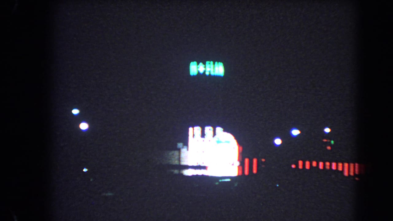 1966 Las Vegas night view with a glowing Flamingo Hotel sign, bright marquee light, streetlights, and dark foreground.