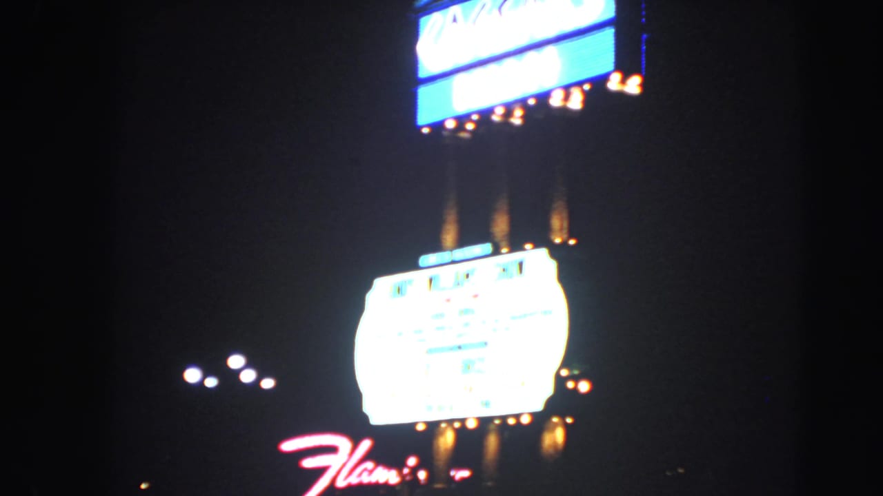 1966 Las Vegas night view with the Flamingo script sign, overexposed marquee, bulbs, and nearby streetlights.