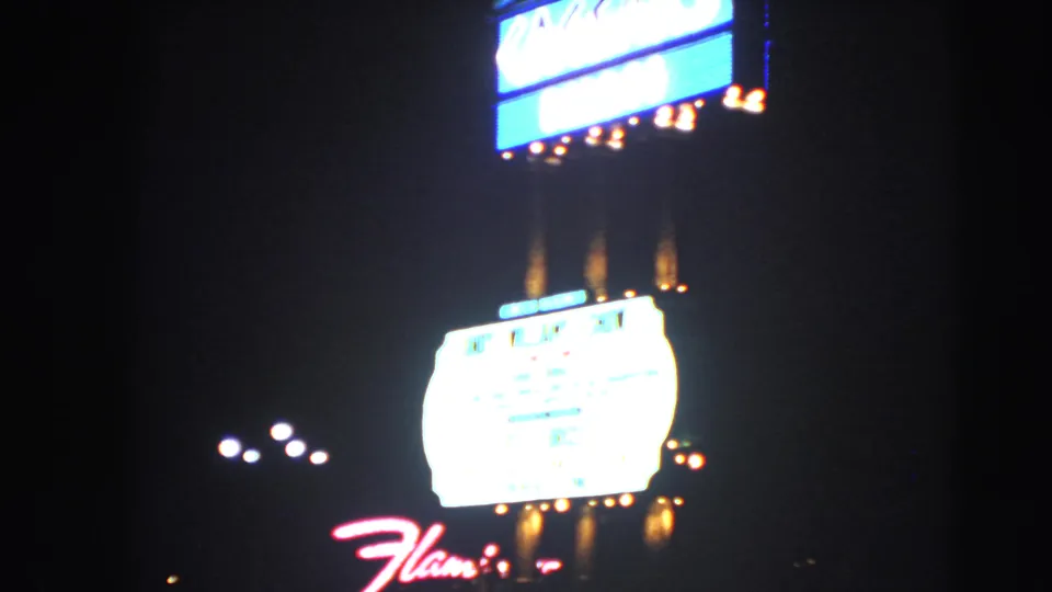 1966 Las Vegas night view with the Flamingo script sign, overexposed marquee, bulbs, and nearby streetlights.