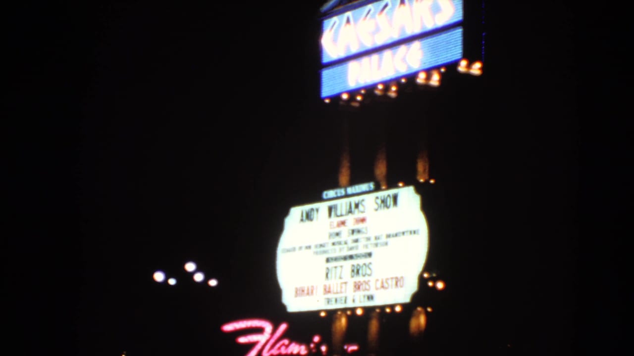 1966 Las Vegas home-movie frame of Caesars Palace neon and marquee signage, with soft focus and bright film exposure bloom.