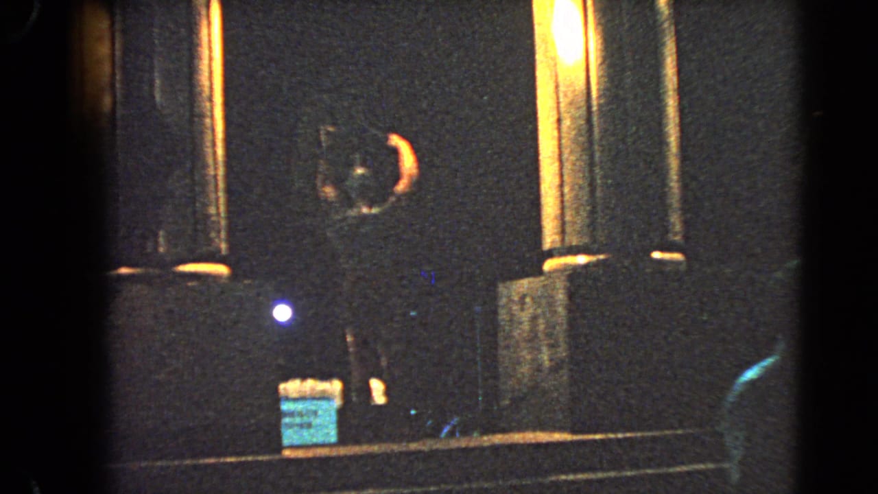 1966 Las Vegas home-movie frame showing a dim roadside display with columns, signage, and colored light.