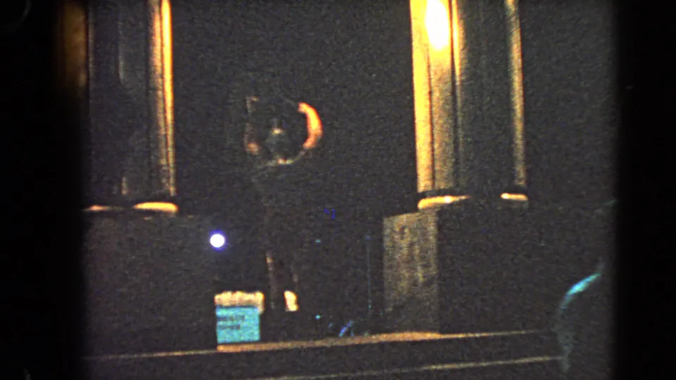 1966 Las Vegas home-movie frame showing a dim roadside display with columns, signage, and colored light.