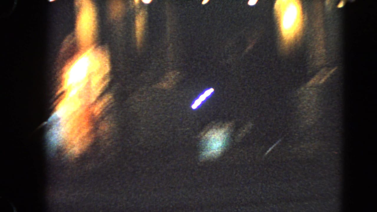Motion-blurred 1966 Las Vegas night frame with warm display lights and colored neon-like points.