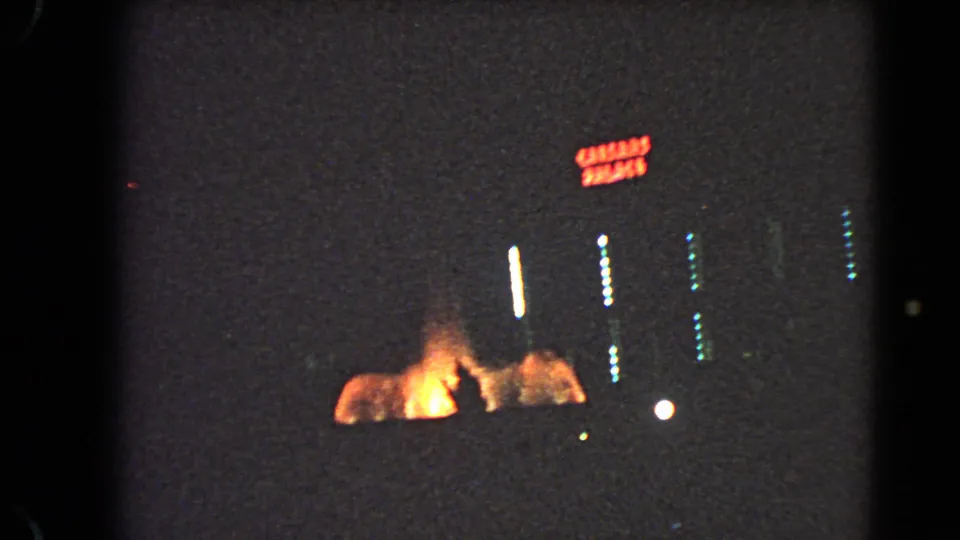 1966 Las Vegas nighttime street view with a red neon sign, bright vertical light streaks, and orange illumination near the ground.