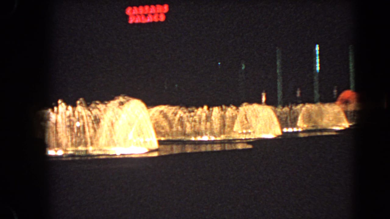 The camera holds on the casino fountain line, with bright water jets and red Caesar's Palace lettering against the night.