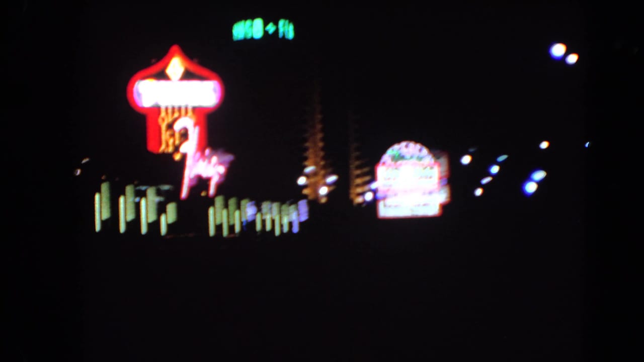 Blurred neon signs and colored lights against a dark Las Vegas night sky.