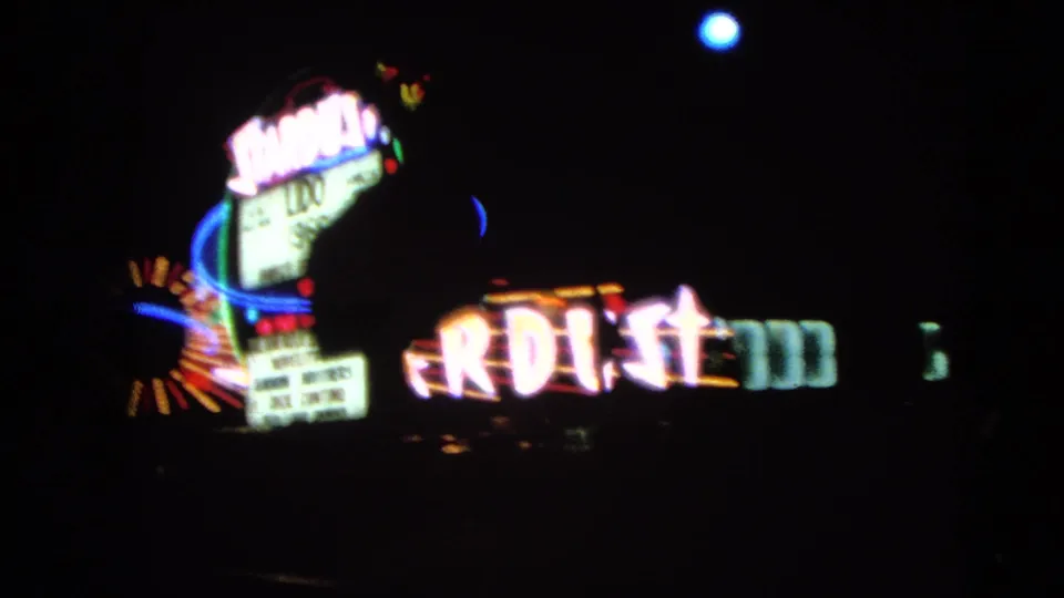 A 1966 Las Vegas frame shows the Gold Key Hotel sign near partial Stardust neon during a night drive.