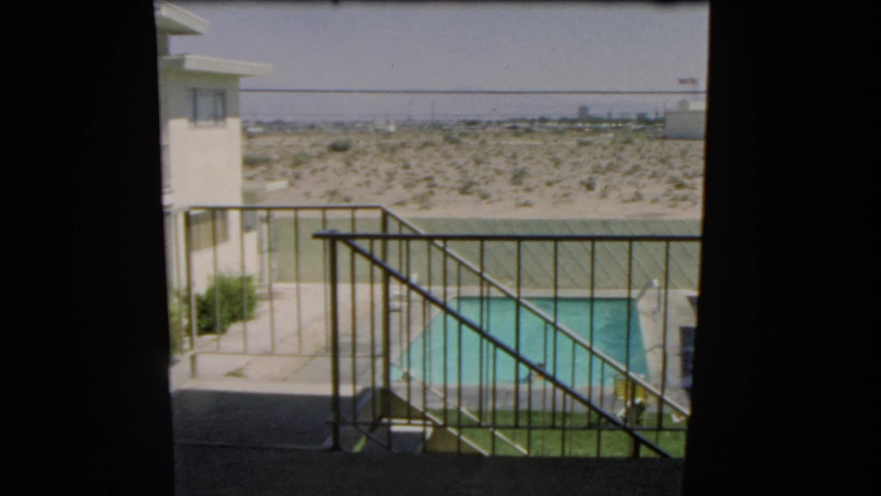 1966 Las Vegas footage frame showing a private pool and swimmer from a shaded balcony, with desert terrain behind the property.