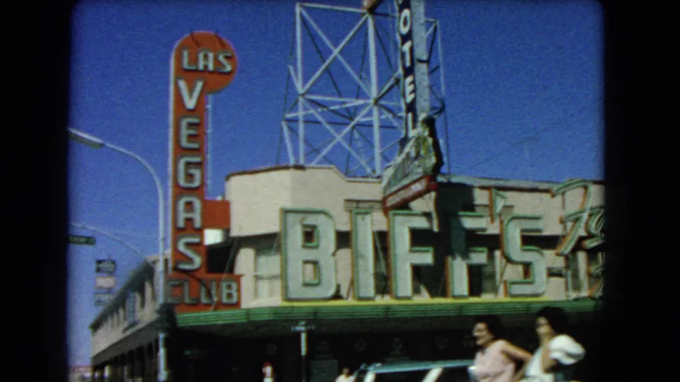 1966 Las Vegas street frame showing Biff's Club, the Las Vegas Club vertical sign, parked or moving cars, and pedestrians.