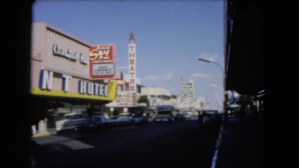 1966 Las Vegas frame with the Mint Hotel sign, Skyline Theatre sign, classic cars, and strong shadow at the right edge.