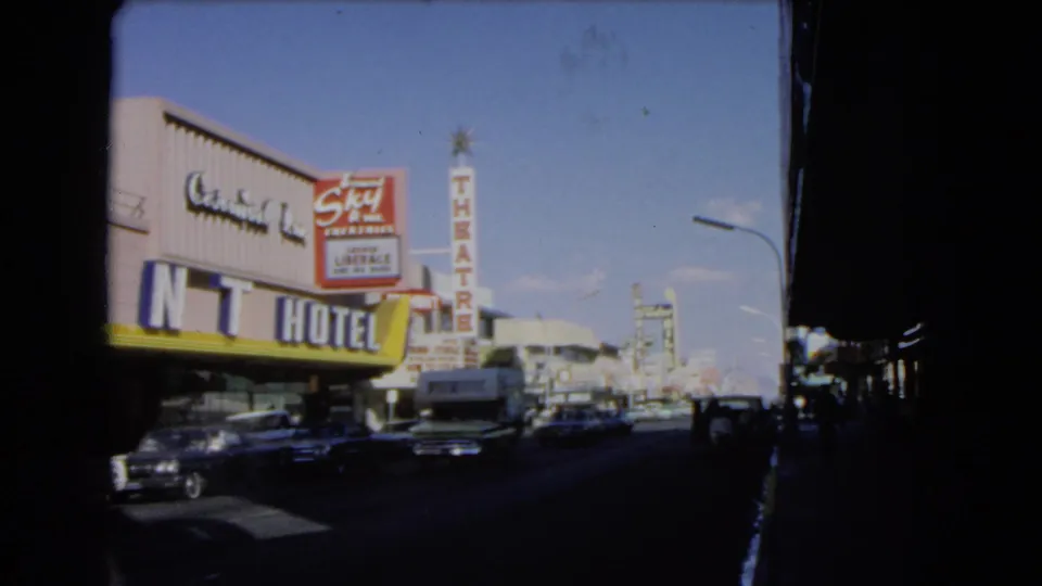 1966 Las Vegas street scene filmed from a car, with Central Inn Hotel signage, Sky Theatre sign, traffic, and storefronts.