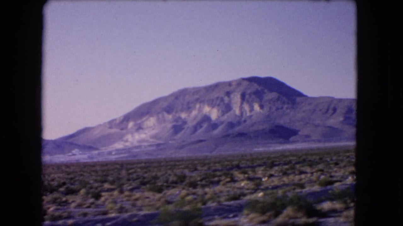 1966 Las Vegas, Nevada 8mm frame showing low desert shrubs and a rugged mountain beyond a broad arid plain.