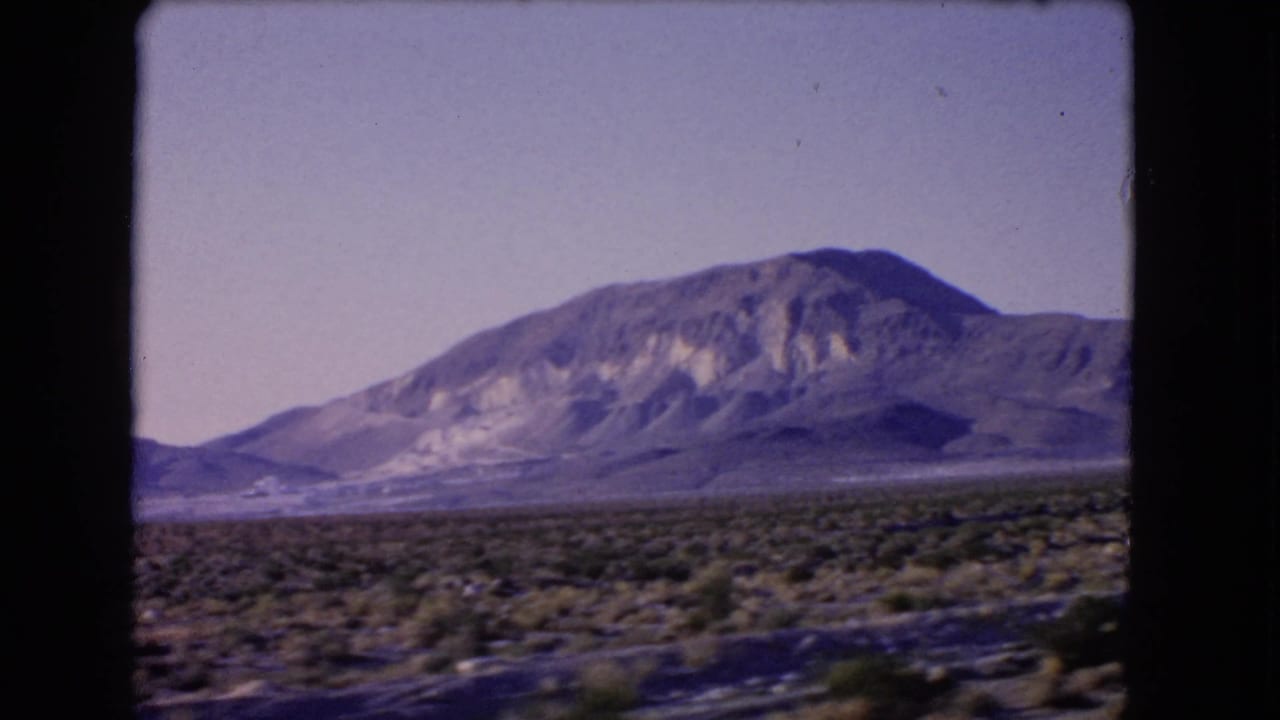 1966 Las Vegas, Nevada frame with a scrubby desert foreground, distant mountain slopes, and slight travel blur.