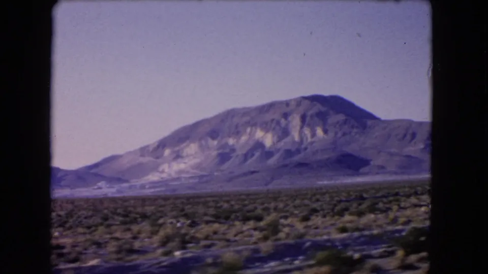 1966 Las Vegas, Nevada frame with a scrubby desert foreground, distant mountain slopes, and slight travel blur.