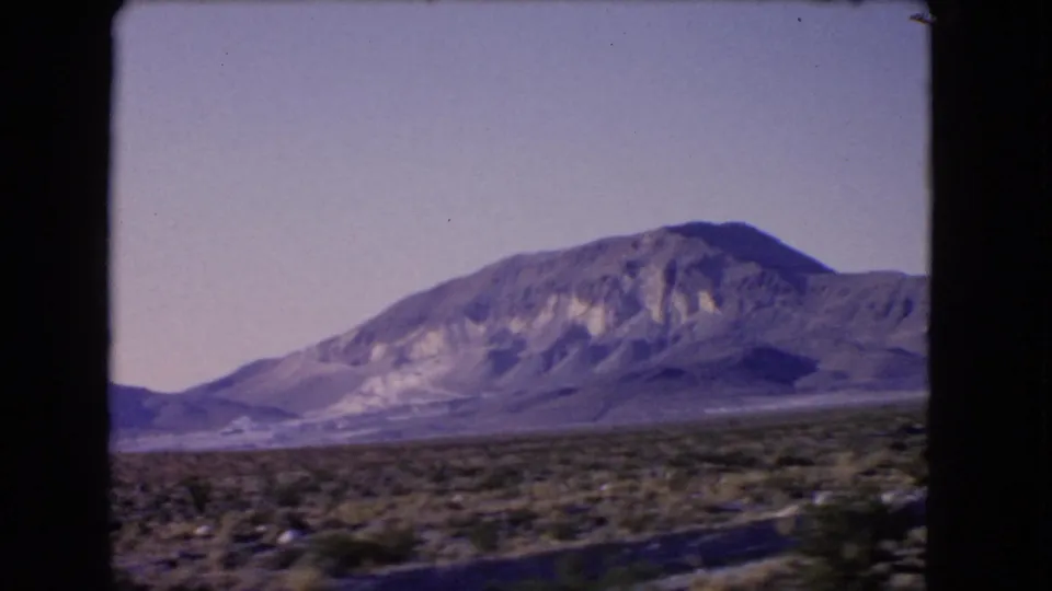 1966 Las Vegas, Nevada 8mm still showing an arid plain, scattered shrubs, and a prominent mountain under washed color.