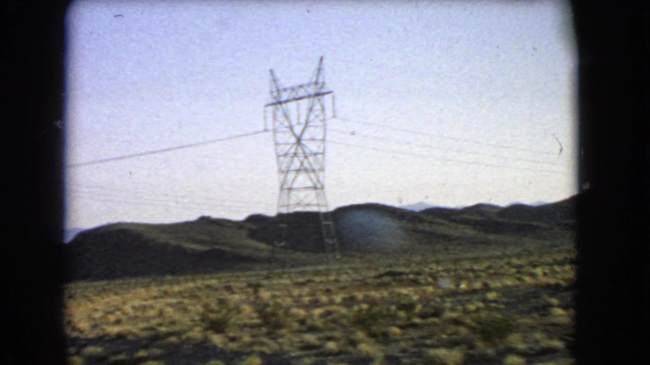 Tall power transmission tower and overhead lines stand across a 1966 Nevada desert roadside landscape.