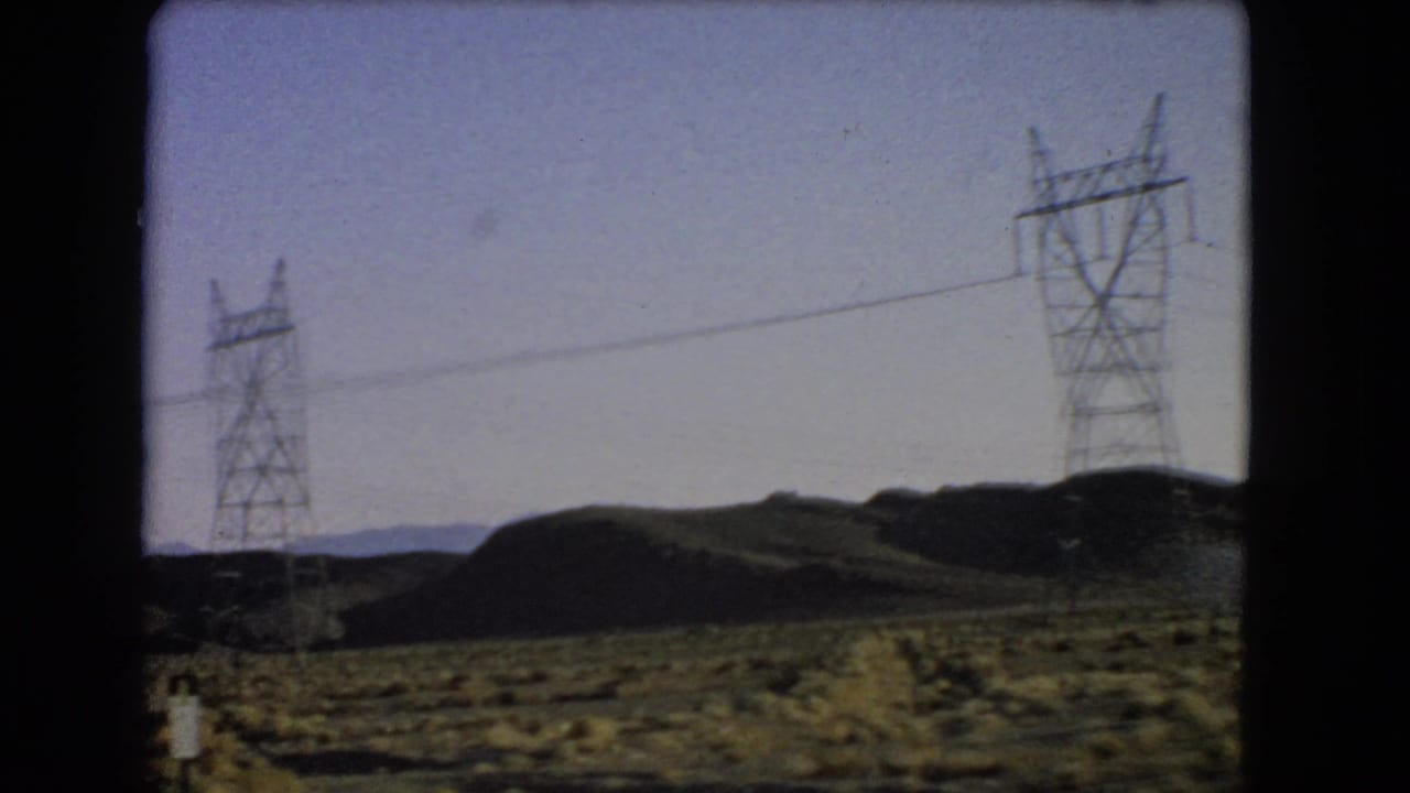 1966 Las Vegas-area desert roadside view with utility towers crossing scrubland and low hills in the distance.