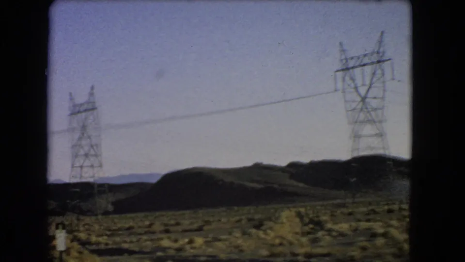 1966 Las Vegas-area desert roadside view with utility towers crossing scrubland and low hills in the distance.