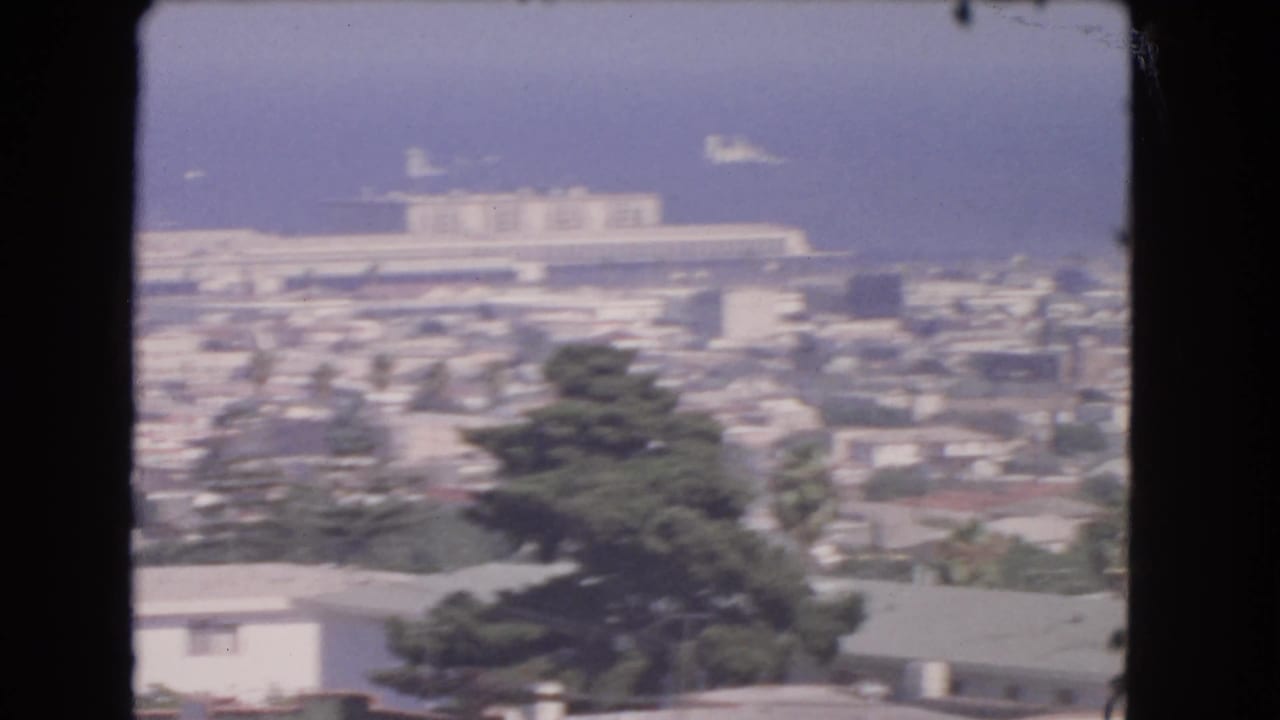 1966 8mm view from above Los Angeles coastal homes and trees, with the ocean and harbor area in the distance.