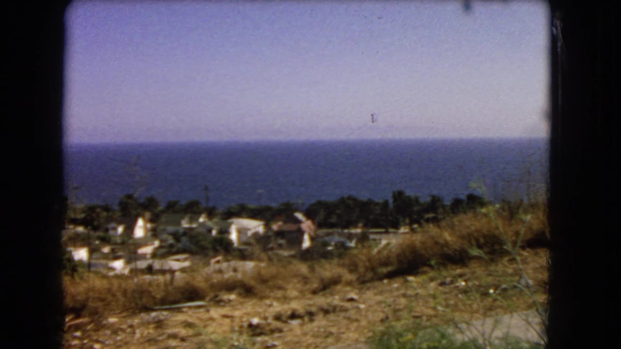 Los Angeles-area coastal overlook in 1966, with hillside scrub in front of homes and a wide blue ocean horizon beyond.