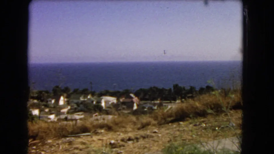 Los Angeles-area coastal overlook in 1966, with hillside scrub in front of homes and a wide blue ocean horizon beyond.